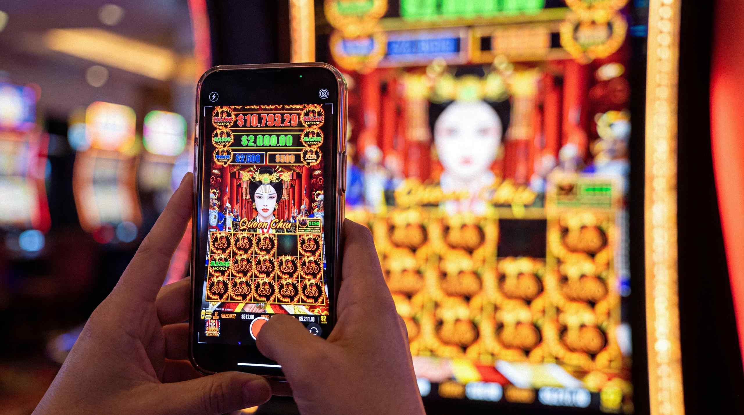 A man using a smartphone to take a photo of a slot win.